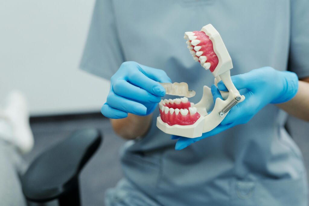 pexels photo 4269700 4269700 Close-up of a dental professional demonstrating with a teeth model in a clinic setting.